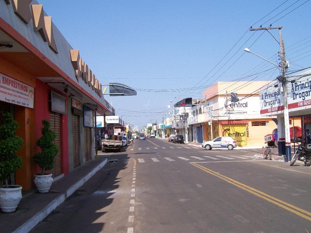 Rua comercial de Bacabal, no Maranhão, com lojas de ambos os lados, faixa de pedestres e céu azul