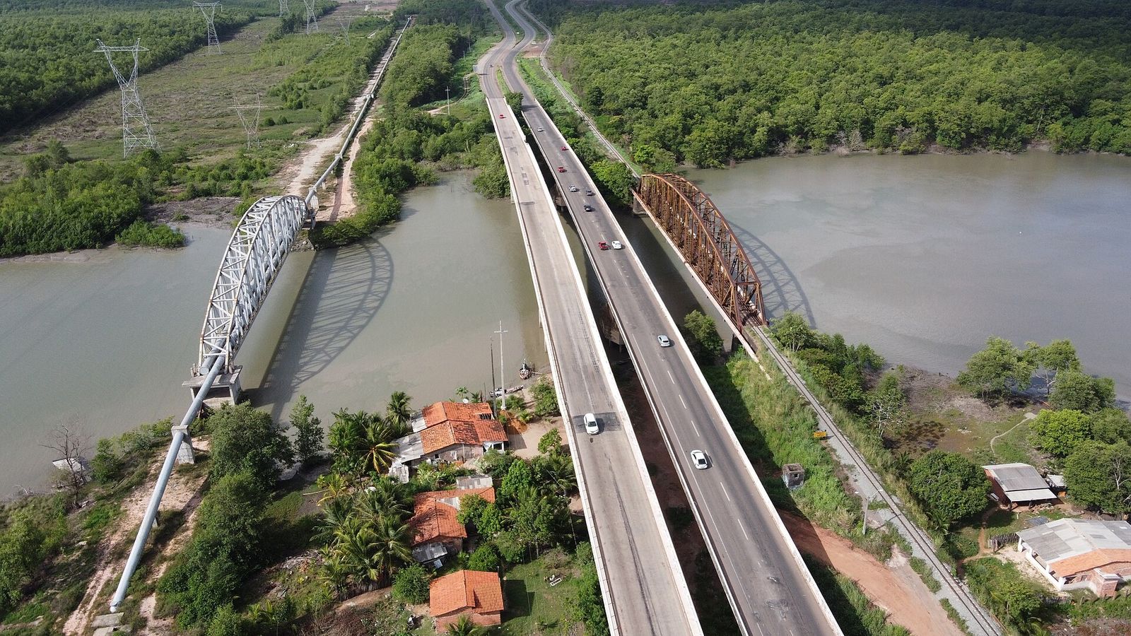 Vista aérea do Estreito dos Mosquitos: ponte rodoviária ao centro, ponte metálica ferroviária à direita e adutora em arco à esquerda, cercadas de manguezal