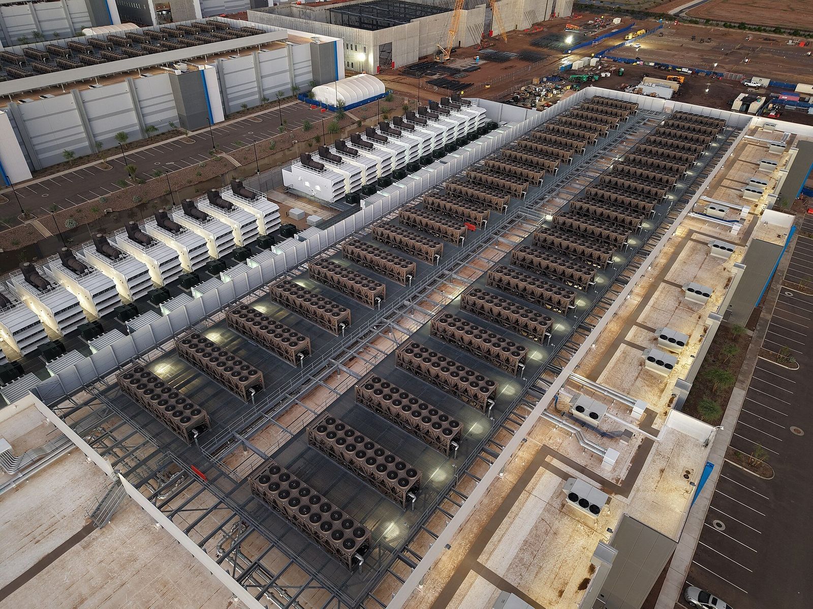 Vista aérea do telhado de um data center, com fileiras de equipamentos de resfriamento e geradores ao lado do prédio