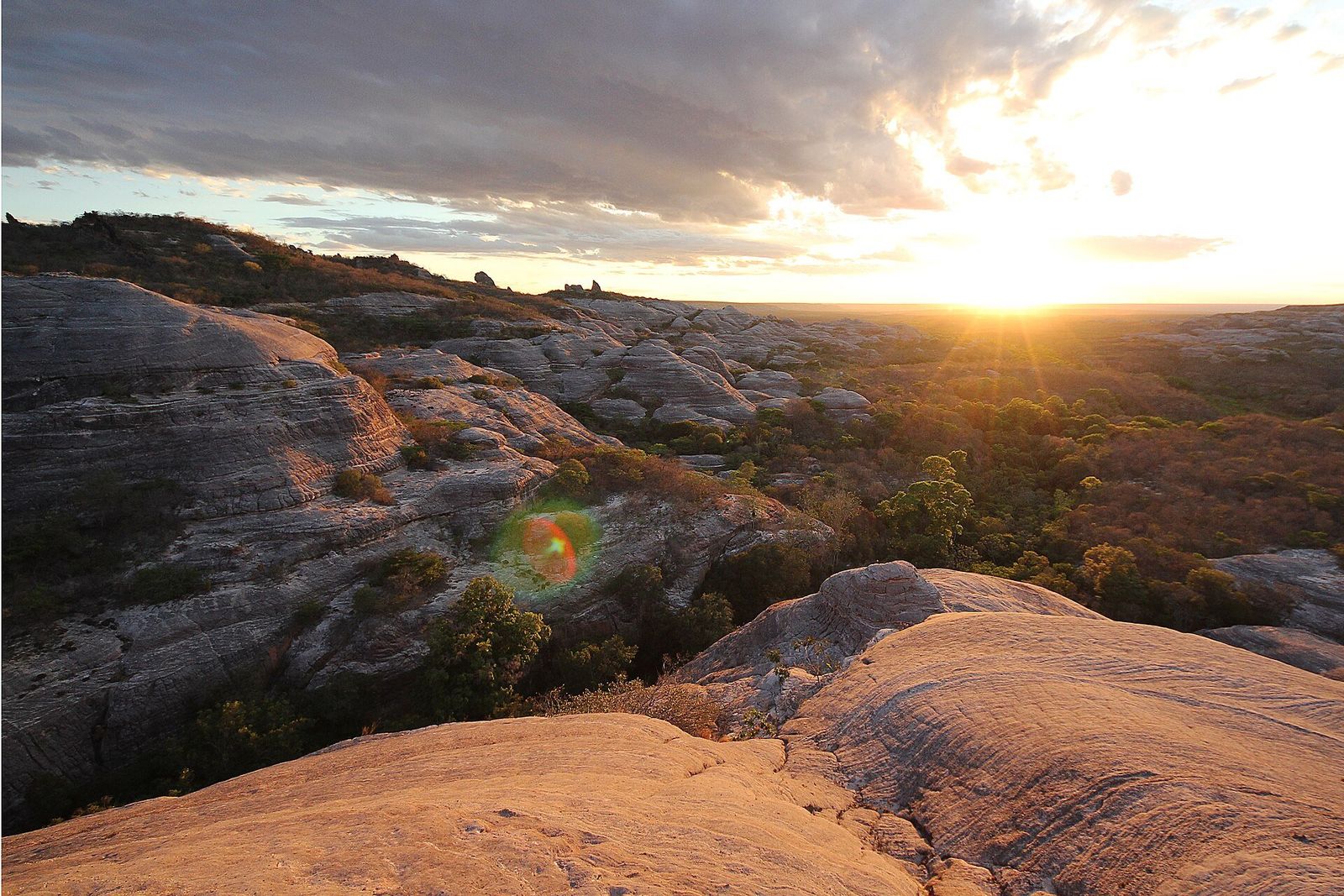 Pôr do sol sobre um planalto de rochas de arenito e vegetação de caatinga