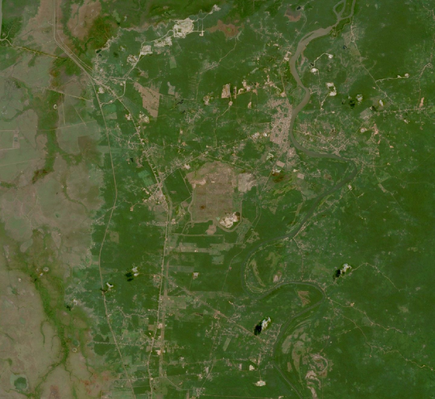 Imagem de satélite com uma grande área plana e clara ao centro, cercada por mata, estradas e povoados; à direita, a cidade de Rosário na curva de um rio