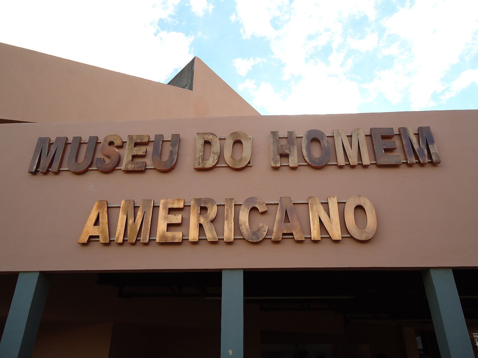 Fachada de prédio rosado com letras de bronze que formam o nome Museu do Homem Americano