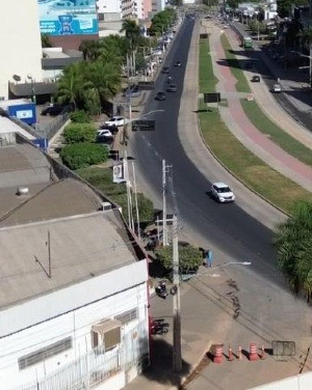 Vista do alto de uma avenida larga em Cuiabá, com canteiro central gramado e pista em obras ao lado